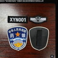 photo - 推特帖文配图。展示了四枚定制的魔术贴徽章，放在红木纹桌面上。徽章内容包括“XYN001”、“药娘 XYN”以及一枚仿警徽设计的蓝色徽章，上面写着“中华人民共和国